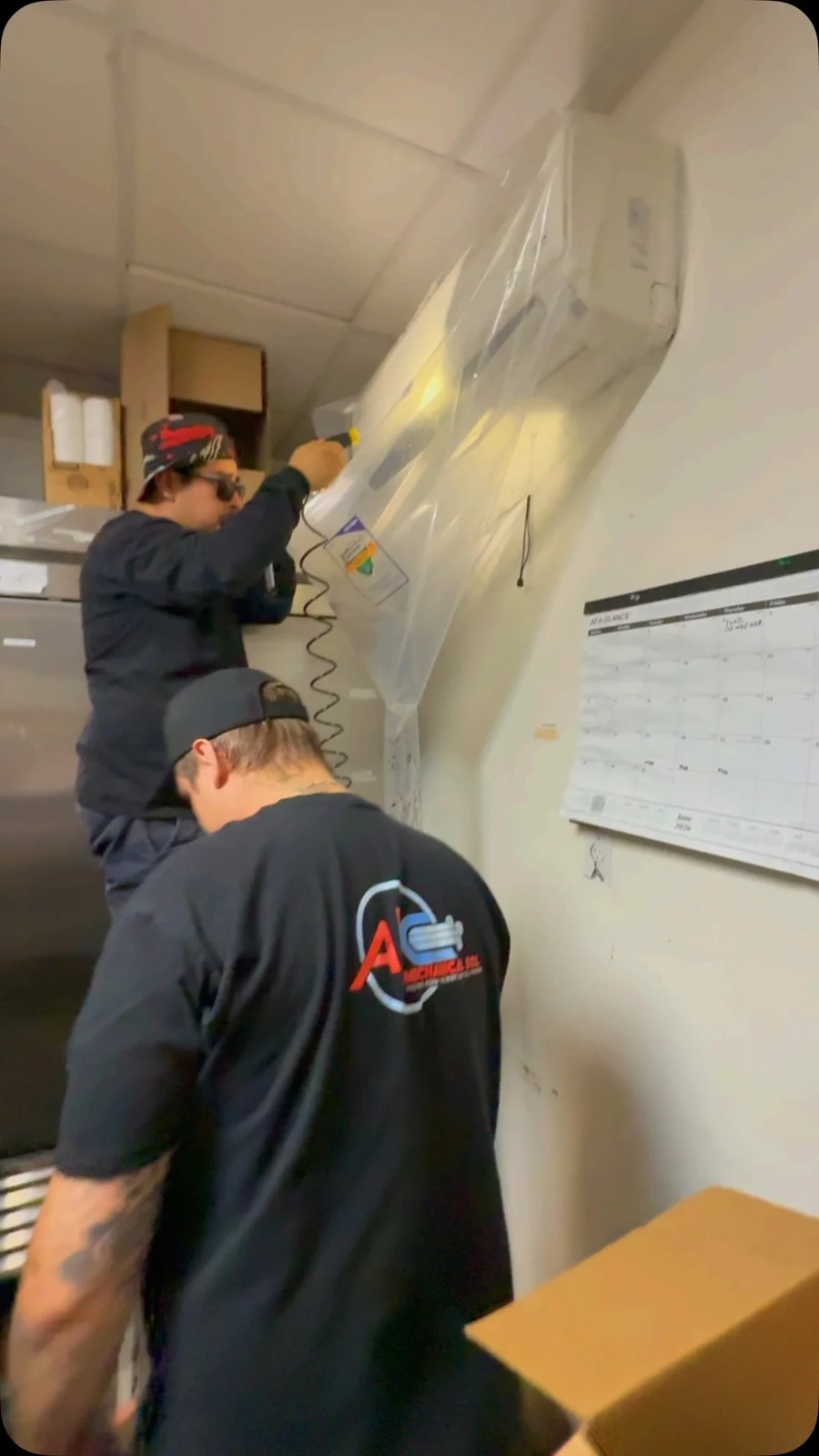 Video still of company technicians cleaning a wall-mounted mini-split.