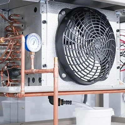 LC Heating and Air technician servicing an outdoor air-conditioning unit.